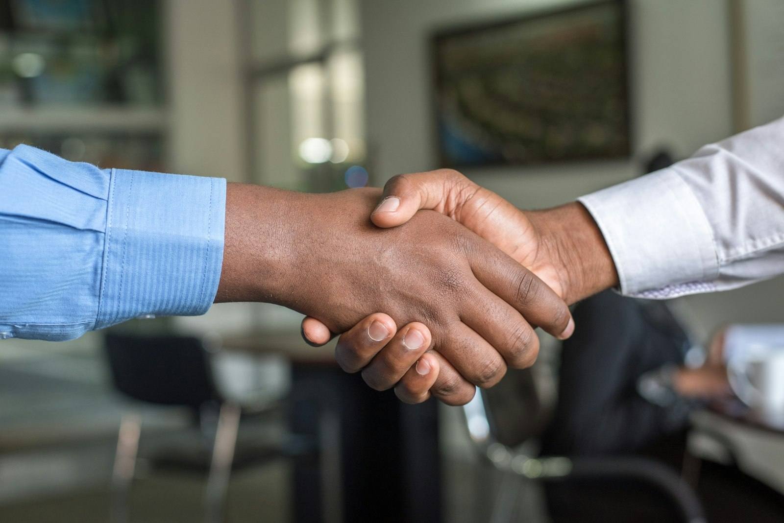 Two people shaking hands over a signed agreement